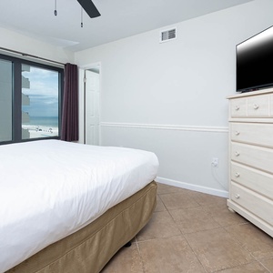 This bedroom features a comfortable bed, a TV for entertainment, and a stunning beachfront view through large windows
