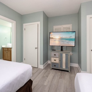 Inviting guest bedroom with two double beds, a large TV, and en-suite bathroom