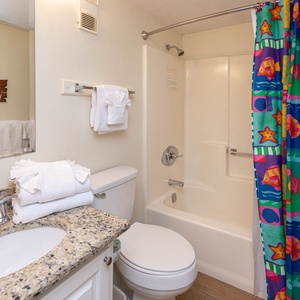 This bathroom features a bright, colorful shower curtain and modern fixtures, perfect for a refreshing retreat
