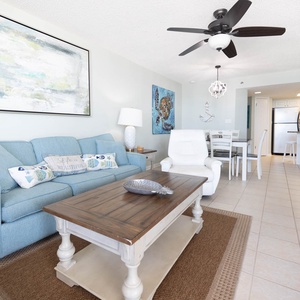 The inviting living area features a light blue sofa with a queen sleeper, a wooden coffee table, and a dining space nearby