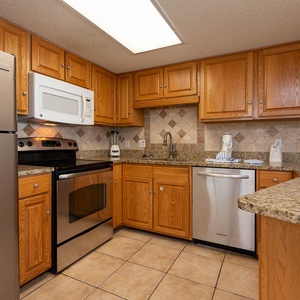Prepare meals in the spacious kitchen featuring essential appliances, ample counter space, and warm wood cabinetry