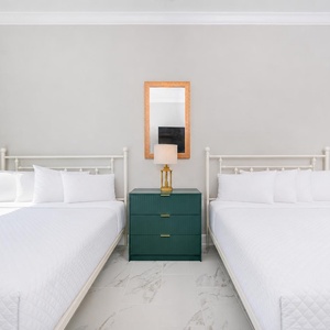 Serene guest bedroom featuring two beds, a stylish nightstand with a lamp, and cozy bedding