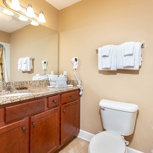 This bathroom features a stylish granite countertop, a palm-patterned shower curtain, and fresh towels for your comfort