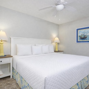 Relax on the king bed in this guest room, surrounded by soft linens and vibrant coastal decor