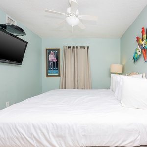 Comfortable guest bedroom features a large king bed, a ceiling fan, and colorful art, creating a relaxing atmosphere