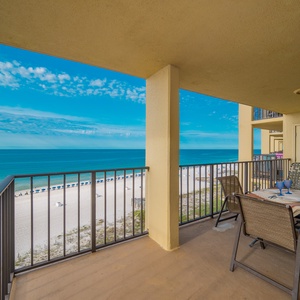 The balcony offers a beautiful view of the beach and vibrant blue sky