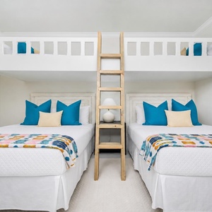 Relax in this playful guest bedroom featuring two queen beds, two lofted twins, and vibrant decor