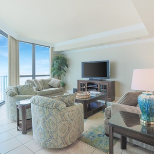 Relax in this inviting living area featuring plush seating, a large TV, and stunning views through expansive windows