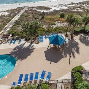 Relax by the inviting pool area, surrounded by lounge chairs and a gazebo, perfect for enjoying the coastal atmosphere