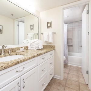 Granite countertops complement the master bathroom featuring a tub/shower combo and neatly arranged fresh towels