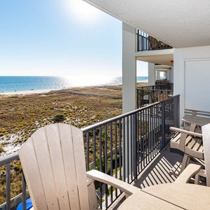 Balcony seating overlooks the beach, offering a serene view of the gulf and the shimmering water beyond