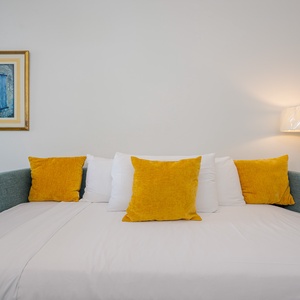 Bright yellow pillows accent a cozy twin bed plus twin trundle, inviting relaxation in a stylish, well-decorated room