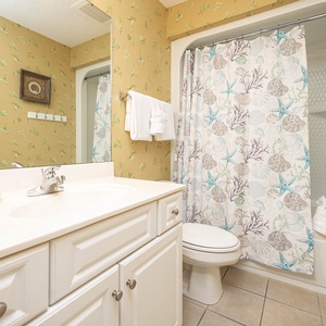 Refresh in this cheerful guest bathroom featuring a spacious vanity, a shower/tub combo, and coastal-themed decor