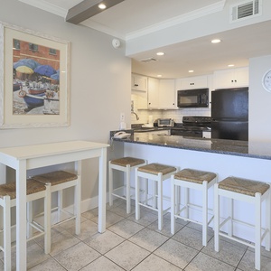 This kitchen features sleek black appliances, granite countertops, and a cozy breakfast bar for casual dining
