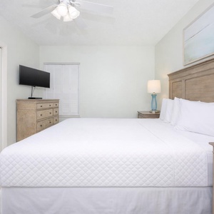 Cozy bedroom featuring a king bed, flat-screen TV, and soft pastel decor, creating a serene retreat for relaxation