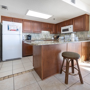The kitchen features rich wooden cabinetry, granite countertops, Keurig, coffee maker, and breakfast bar with stools