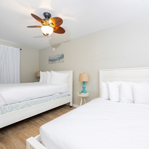 Welcoming guest bedroom featuring two double beds, soft linens, and charming bedside lamps, perfect for a restful retreat