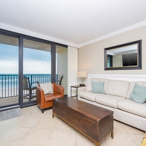 This living area features a cozy sofa and a view of the beach through large sliding glass doors, perfect for relaxation