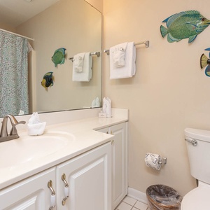 Brightly decorated guest bath features a spacious vanity, colorful fish artwork, and a shower curtain with a vibrant pattern