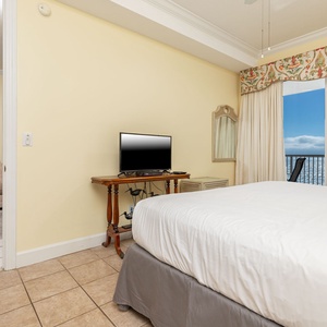 This bedroom features a cozy bed, a TV for entertainment, and a stunning beachfront view through large windows
