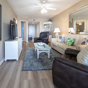 Living area featuring a cream sofa with queen sleeper, a dark recliner, and a large TV with a stylish coffee table