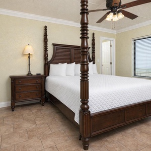 King master suite with a four-poster bed, elegant furnishings, and a window offering a glimpse of the area
