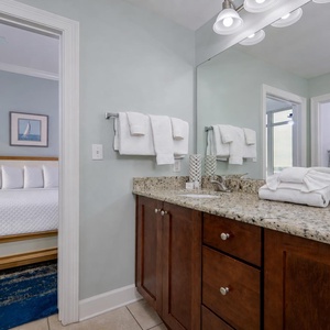 Smooth granite countertops are set for your morning routine in this guest bathroom with plush towels nearby