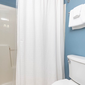 This guest bathroom features a white shower curtain, fresh towels, and soothing blue walls for a refreshing experience