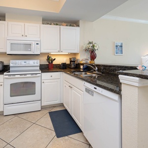 This kitchen features sleek white cabinetry, granite countertops, and essential appliances, perfect for preparing meals