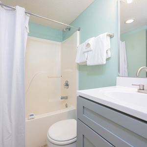 Refresh in this bathroom featuring a spacious vanity, soft teal walls, and a shower with a curtain for privacy