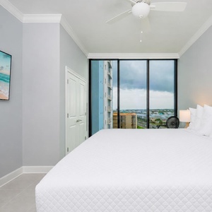 Serene guest bedroom featuring a king bed, a TV, and large windows that frame inviting views of the surroundings