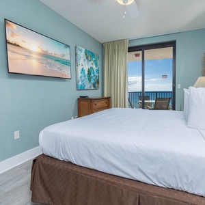 Relax in the comfortable master bedroom featuring a plush king bed, a large TV, and balcony with beautiful views