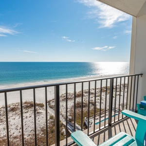 Enjoy stunning beachfront views from this inviting balcony with colorful seating, perfect for relaxation and sunsets