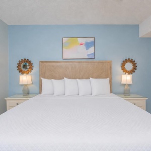 White pillows rest against the headboard in the king suite where gentle lamps glow beside you