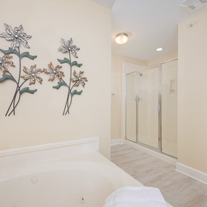 Relax in this inviting master bathroom featuring a jetted tub, walk-in shower, and charming floral wall decor