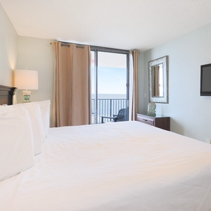 Experience restful nights in this inviting master bedroom, featuring a king bed, stylish decor, and beach balcony access