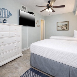 The guest bedroom features two comfortable beds, a large TV, and charming coastal decor for a relaxing stay