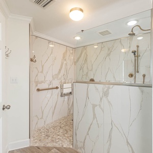 Experience an elegant and spacious walk-in shower with brilliant tile, a rainfall showerhead, and a stylish glass enclosure