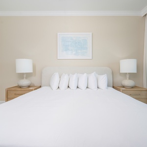 Spacious master suite featuring a king bed, fluffy pillows, and beachfront balcony access
