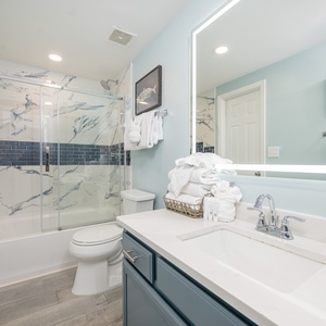 Marble-patterned shower and neat towels invite you to refresh and unwind in the guest bath