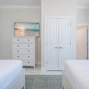 Cozy guest bedroom with two queen beds, a stylish rug, and a TV for streaming your favorite shows
