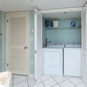 A convenient laundry area features a washer and dryer, complemented by light blue walls and tiled flooring