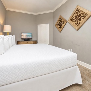 This cozy guest bedroom features a king bed, a TV for entertainment, and decorative wall art for a relaxing stay