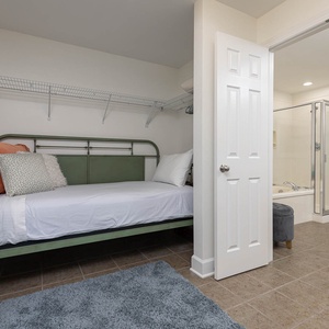 Two twin green metal beds are featured in the master closet adorned with soft pillows and a cozy rug for your comfort