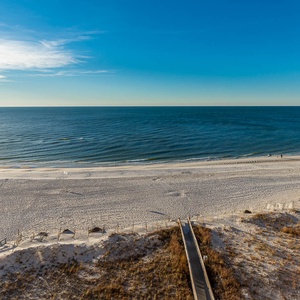 Beachfront view showcases soft white sand and gentle waves under a clear blue sky, inviting relaxation and exploration