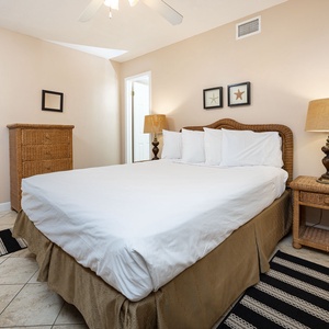 Cozy guest bedroom featuring a plush queen bed, wicker furniture, and warm lighting for a relaxing retreat