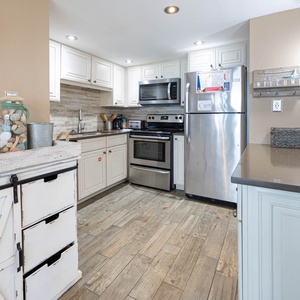 Kitchen featuring stainless appliances, coastal decor, breakfast bar, and a welcoming atmosphere for culinary adventures