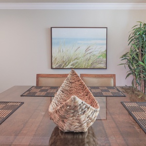 Elegant dining table, accented by a decorative basket and framed beach artwork for a welcoming atmosphere