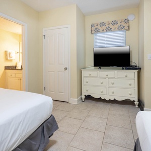 Relax in the comfortable guest bedroom featuring two double beds, a TV, and easy access to the adjoining bathroom