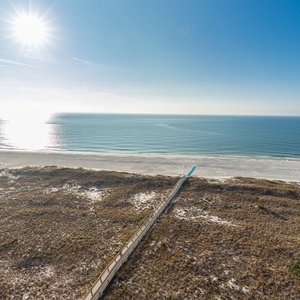 Glowing sand meets the tranquil gulf waters under a bright sun, creating a serene beach atmosphere perfect for relaxation